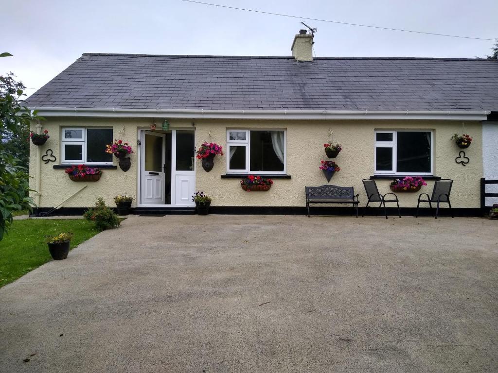 a house with two benches in front of it at Cub Cottage in Kilcoo