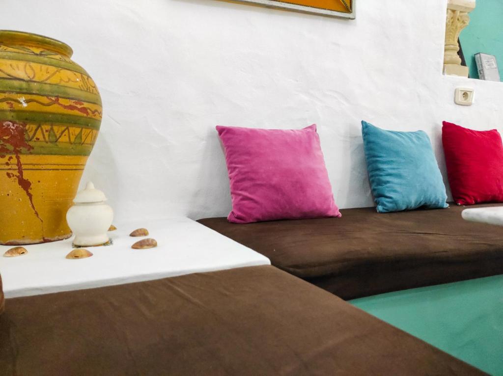 a room with a couch with colorful pillows and a vase at The Shell Of The Beach in Hammamet