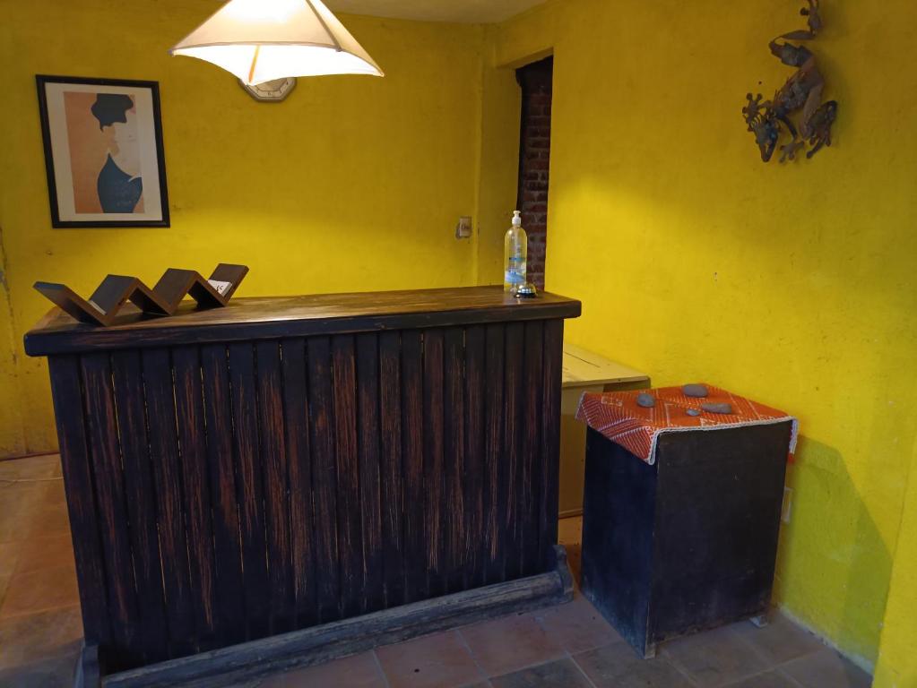 a wooden bar in a yellow room with a lamp at El Arrayan in Valle de Bravo