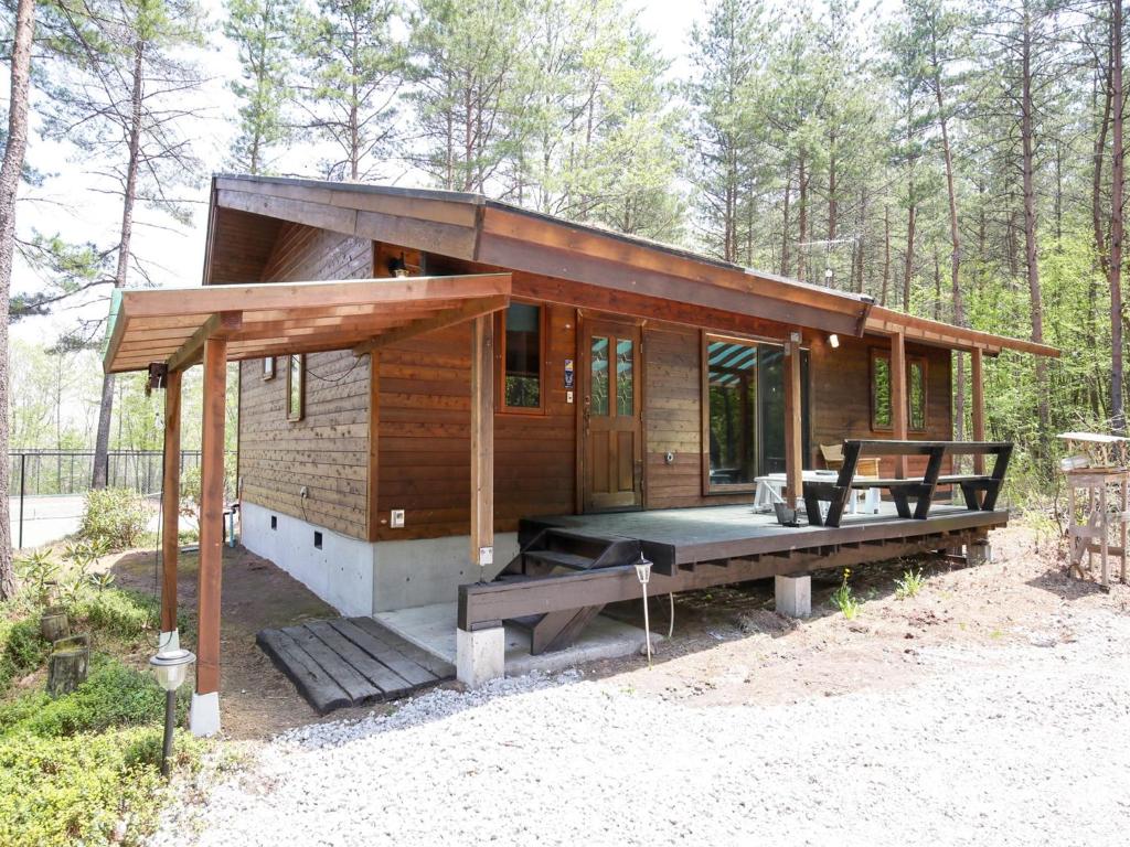 a small wooden cabin with a porch in the woods at Runesu Karuizawa - Vacation STAY 92236v in Tsumagoi