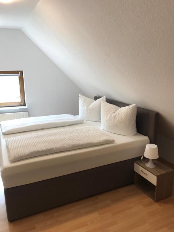 Ferienwohnung Haus Maja في Holzkirchen: سرير بشرشف ووسائد بيضاء في الغرفة