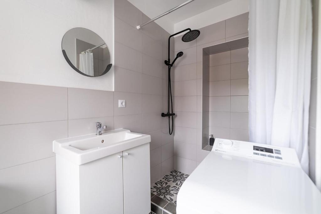 La salle de bains blanche est pourvue d'un lavabo et d'un miroir. dans l'établissement Apartaments Nr.33 (Viesu Nr.3), à Talsi