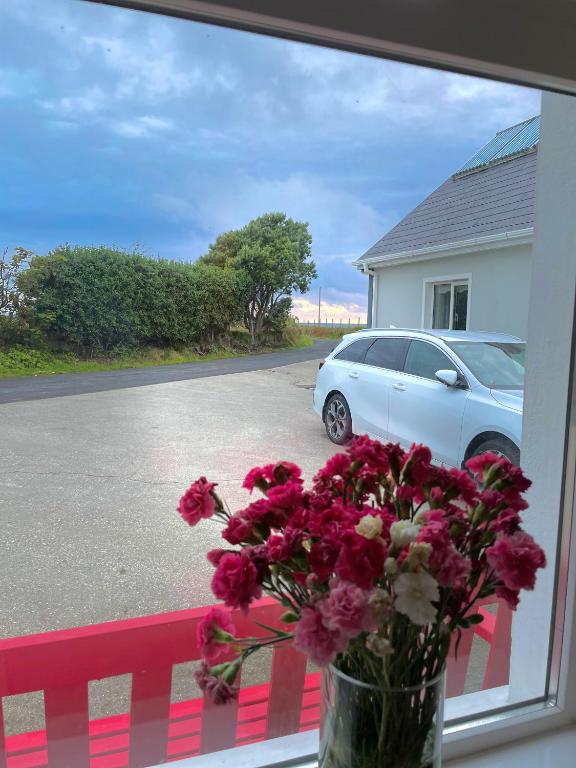 a vase of flowers sitting on a window sill with a car at Whitestrand B&B in Malin Head