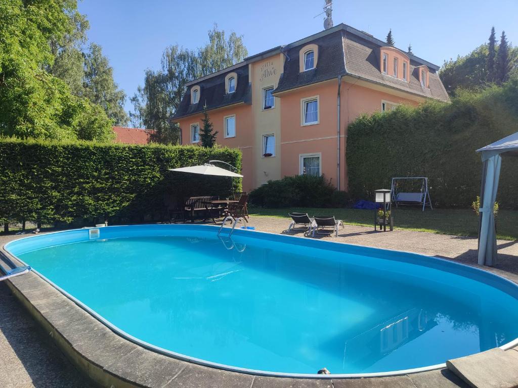 a large blue swimming pool in front of a house at Villa Anzio in Mariánské Lázně