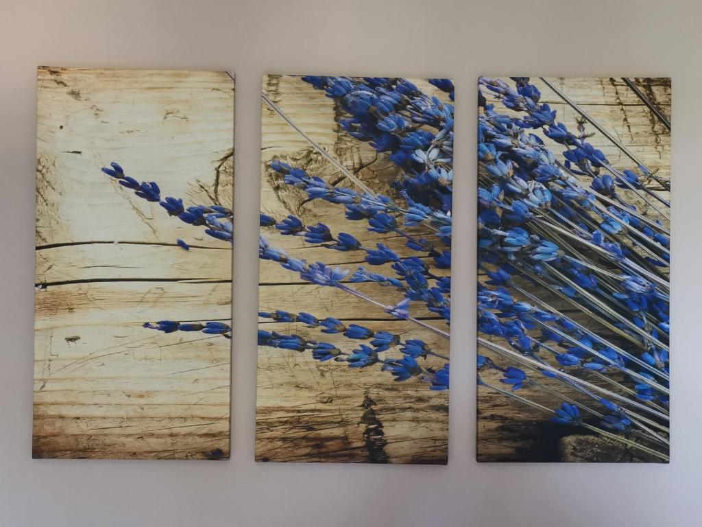 three paintings of blue flowers on a wooden table at ELVAJO Apartment in Zakharo