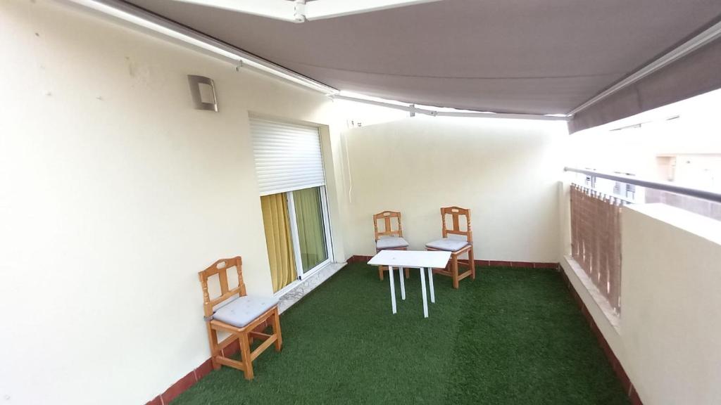 2 Stühle und ein Tisch in einem Zimmer mit grünem Teppich in der Unterkunft Ático Roquetas in Roquetas de Mar