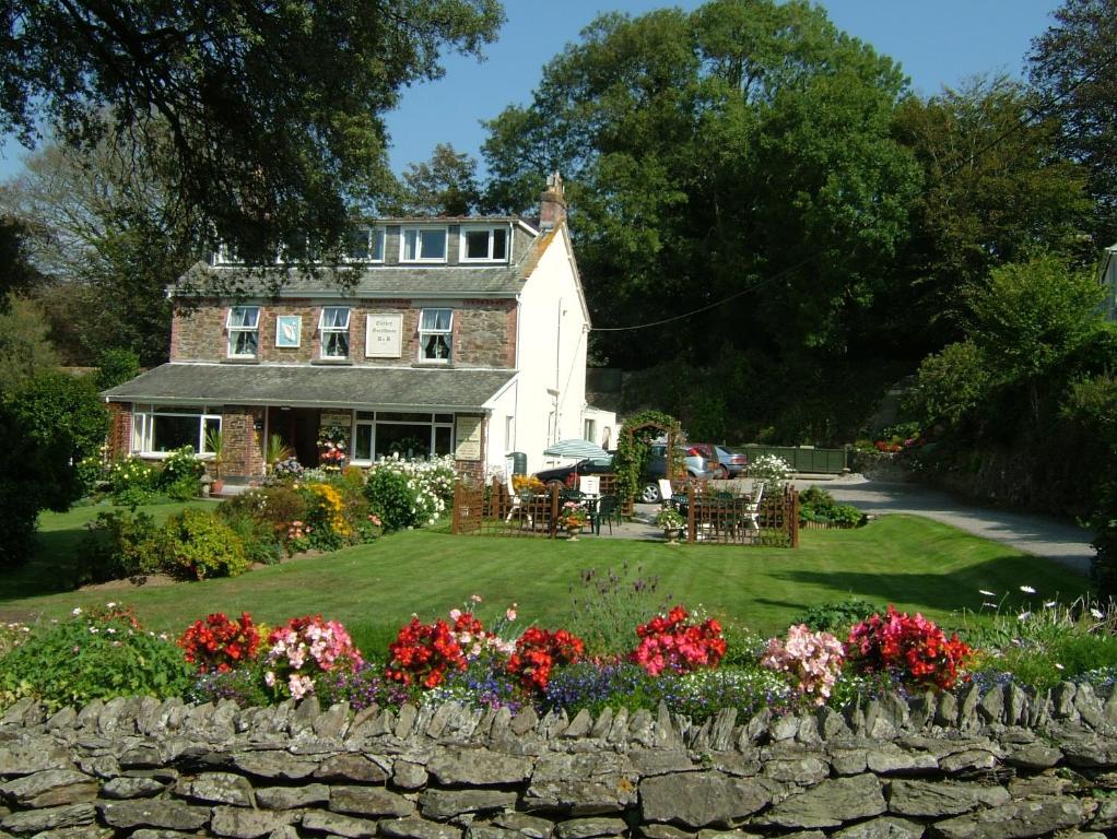a house with a stone wall and flowers in the yard at Elerkey Guest House in Veryan