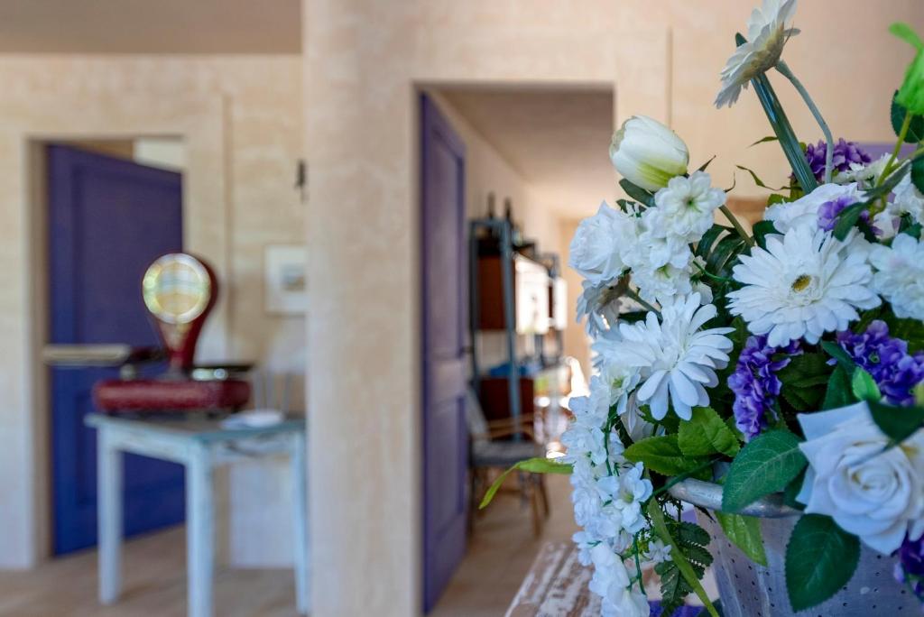 un jarrón lleno de flores blancas y moradas en una habitación en Lu Casal de Fiò en Alguer