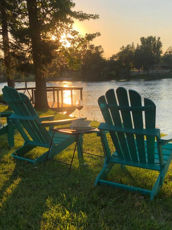 Luxury Riverside Estate - 3BR Home or 1BR Cottage or BOTH - Sleeps 14 - Swim, fish, relax, refresh في أندرسون: كرسيين وطاولة أمام البحيرة