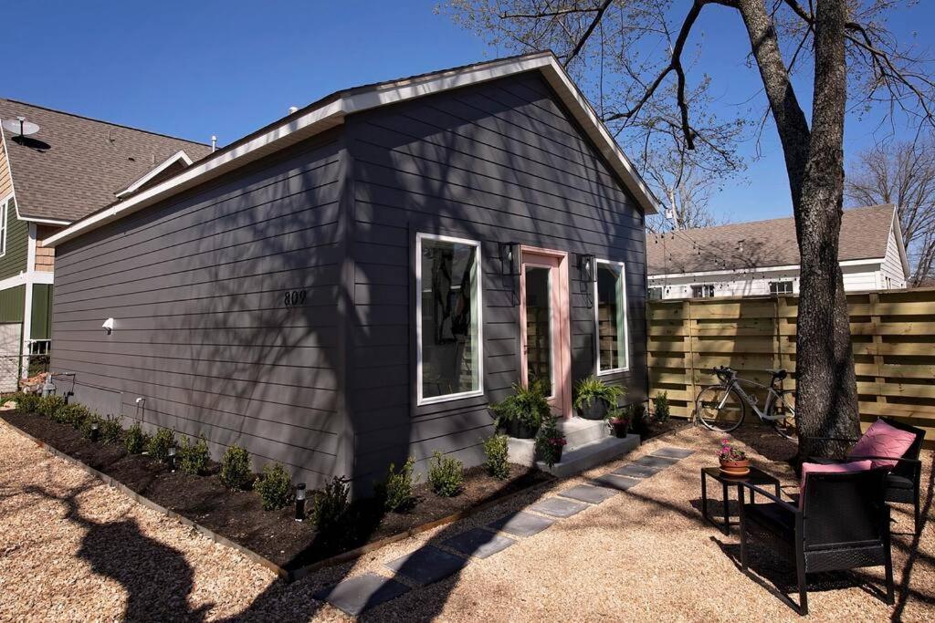 una pequeña casa negra con un árbol delante en The Studio on Ast., Downtown Bentonville near all!, en Bentonville