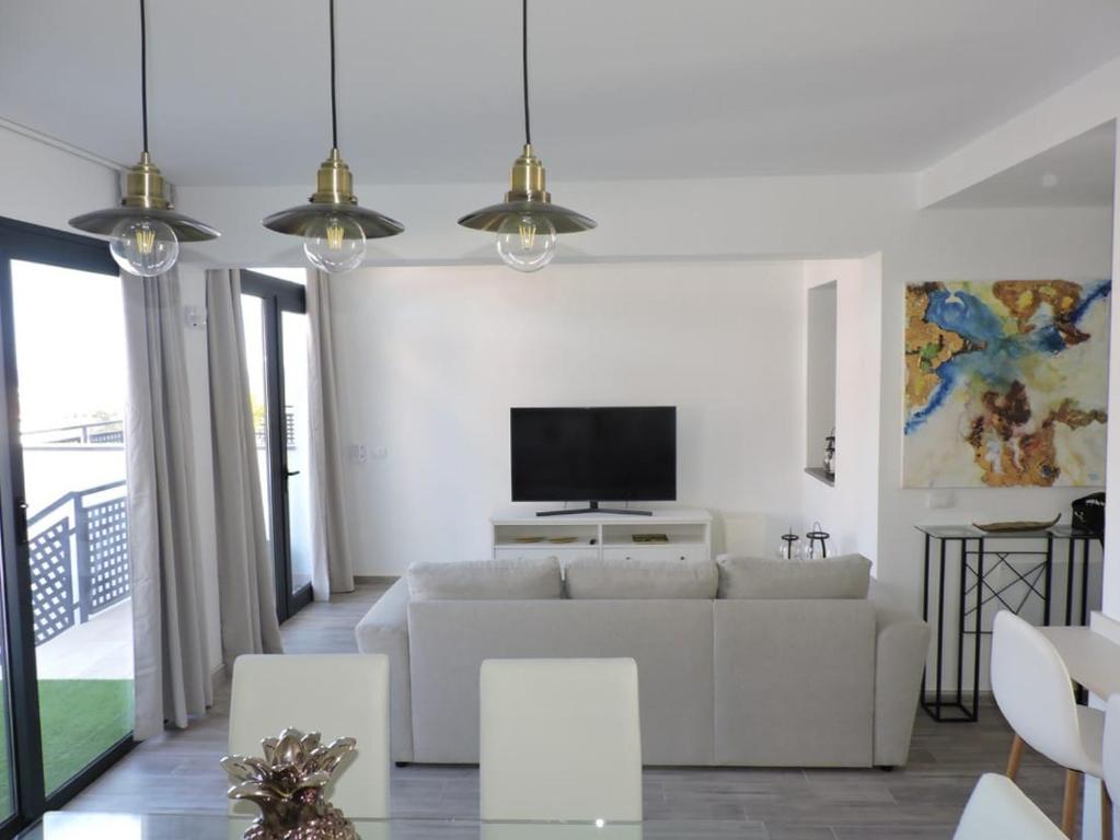 a living room with a white couch and a tv at SUNHILL LUXURIOUS house in Arguineguín