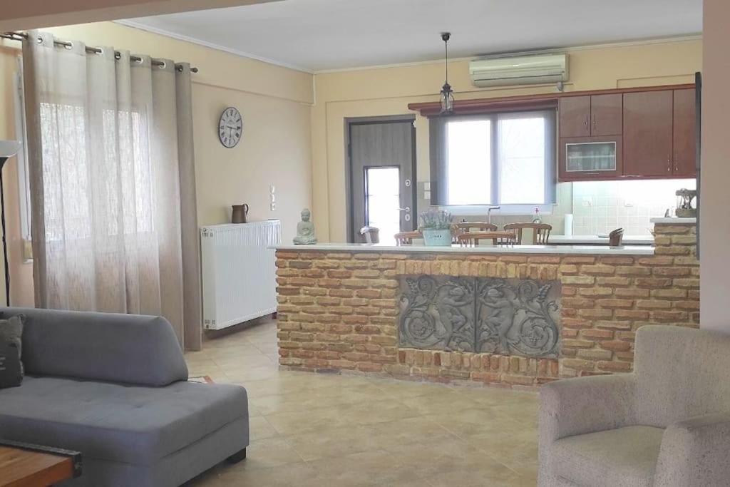 a living room with a brick fireplace and a kitchen at Nikos House Megara in Megara
