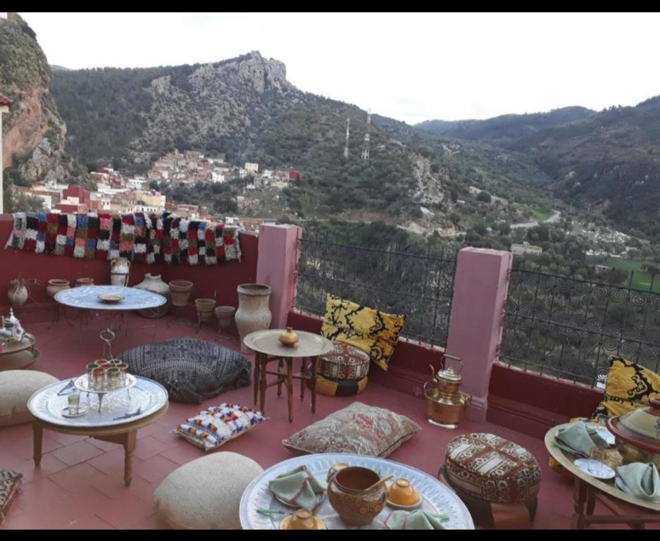a balcony with tables and chairs with mountains in the background at Riad lala zakia in Moulay Idriss Zerhoun