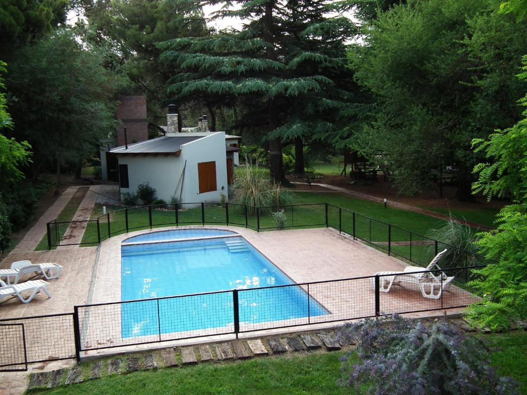 a swimming pool with a fence next to a house at Cabañas La Morera in Villa Ventana