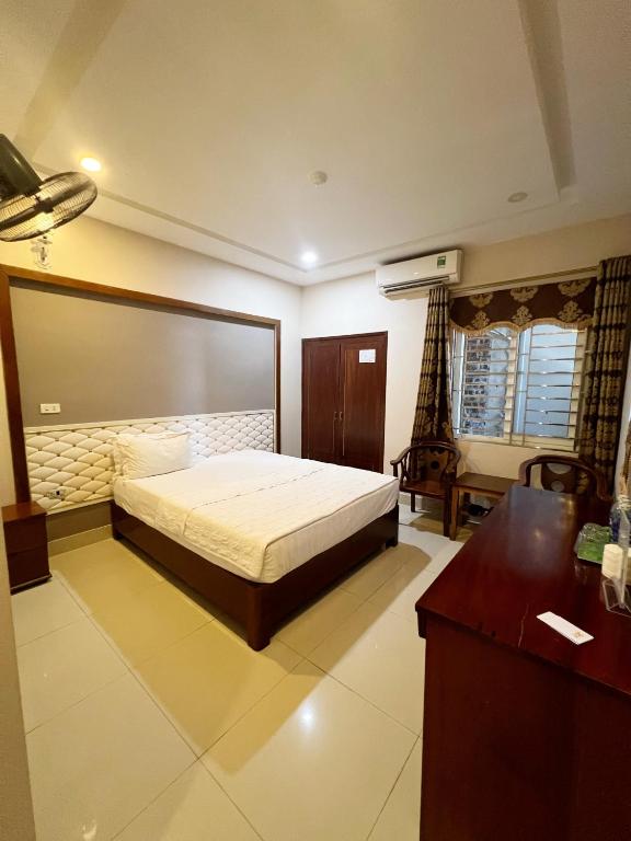 a bedroom with a bed and a desk in it at Hoang Ngan 1 Hotel - TP. Vinh in Vinh