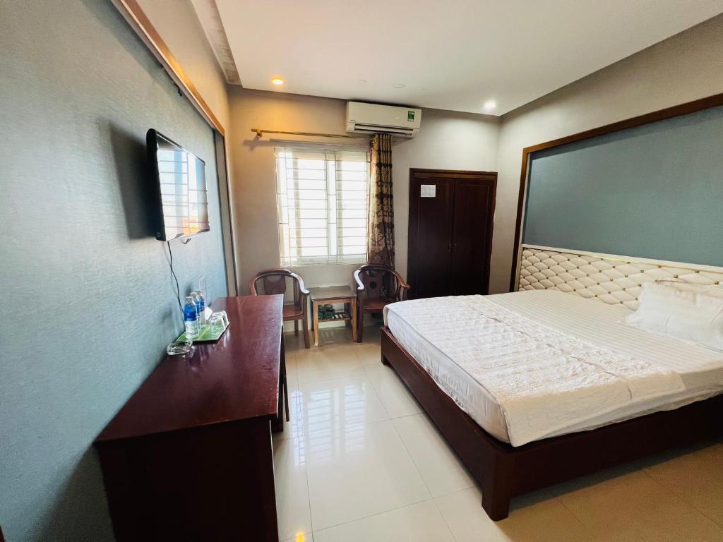 a hotel room with a bed and a desk and a room at Hoang Ngan 1 Hotel - TP. Vinh in Vinh
