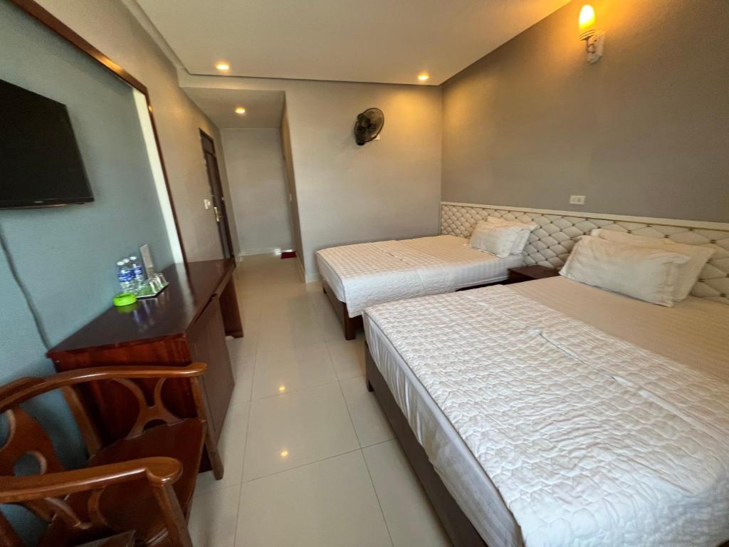 a hotel room with two beds and a flat screen tv at Hoang Ngan 1 Hotel - TP. Vinh in Vinh