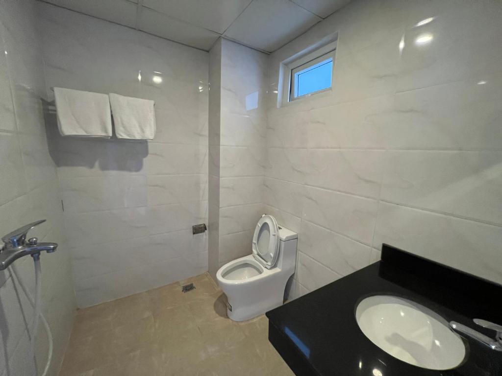 a white bathroom with a toilet and a sink at Hoang Ngan 1 Hotel - TP. Vinh in Vinh