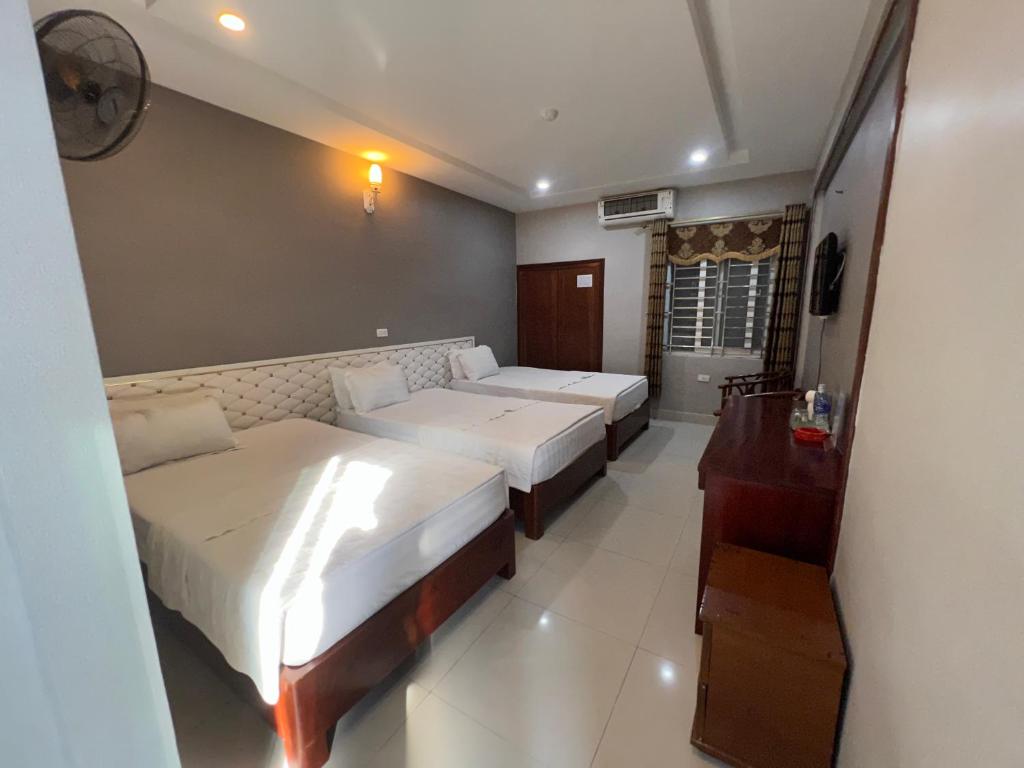 a hotel room with two beds and a desk at Hoang Ngan 1 Hotel - TP. Vinh in Vinh
