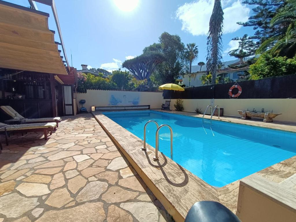a swimming pool in a yard with a stone patio at Finca Paraiso Monturrio Oase der Ruhe in La Orotava