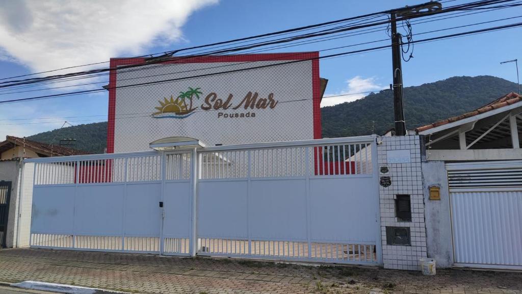 um edifício branco com um sinal na lateral em Sol Mar Pousada na Praia Grande