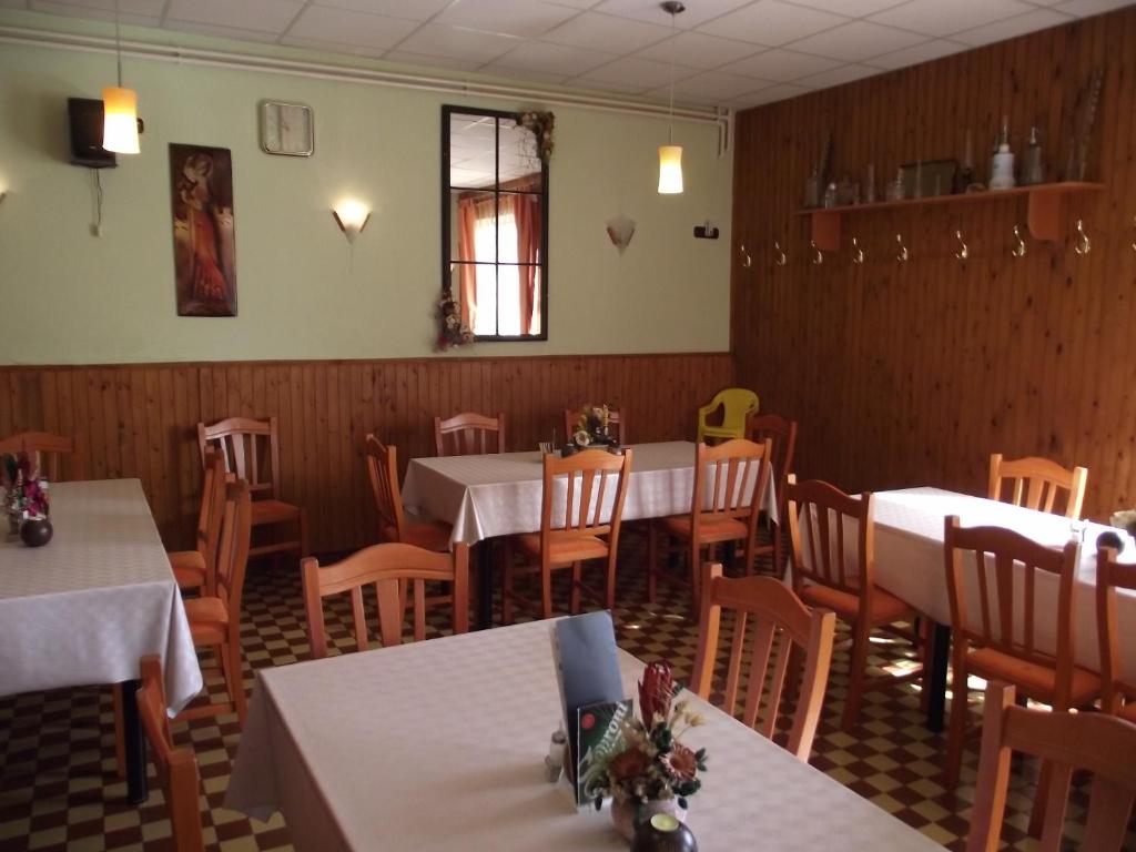 ein Esszimmer mit weißen Tischen und Holzstühlen in der Unterkunft Ludas Fogadó in Nagyalásony