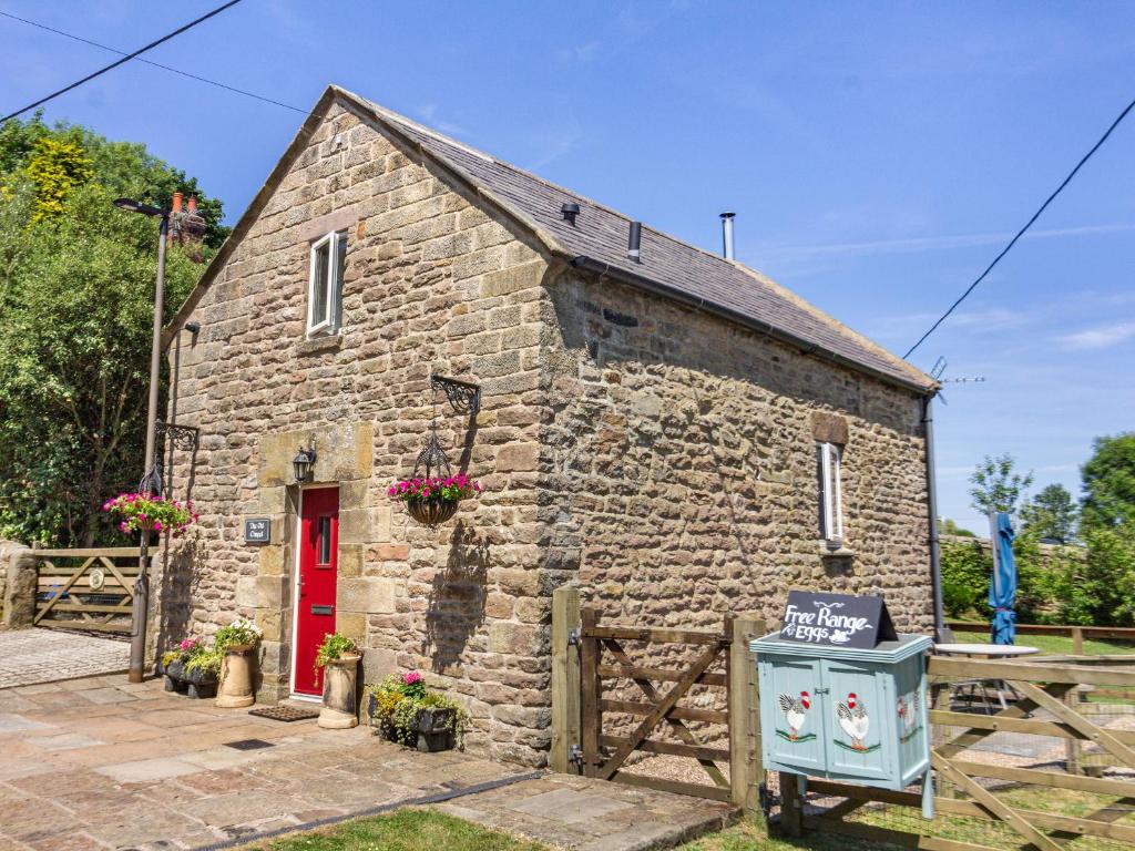 a stone house with a red door and a sign in front at The Old Chapel in Matlock