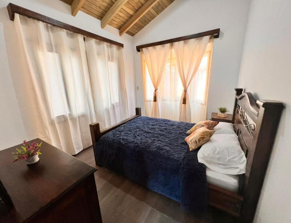 a bedroom with a bed and a table and windows at Villas Gasconia in Antigua Guatemala