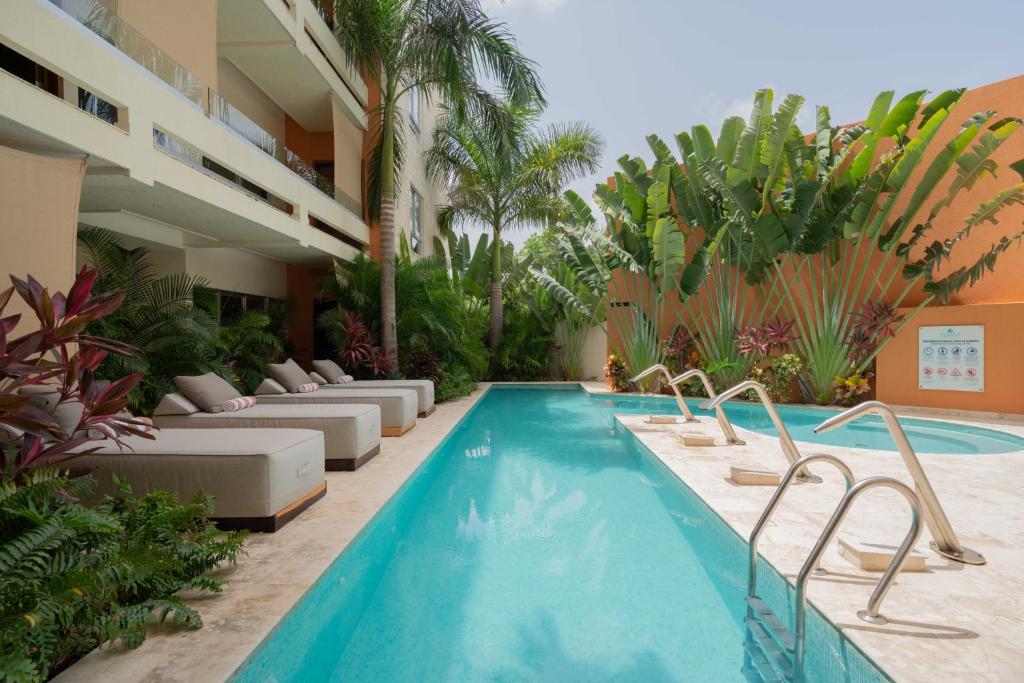 a swimming pool with lounge chairs next to a building at Valhalla Residences by Biwa in Tulum