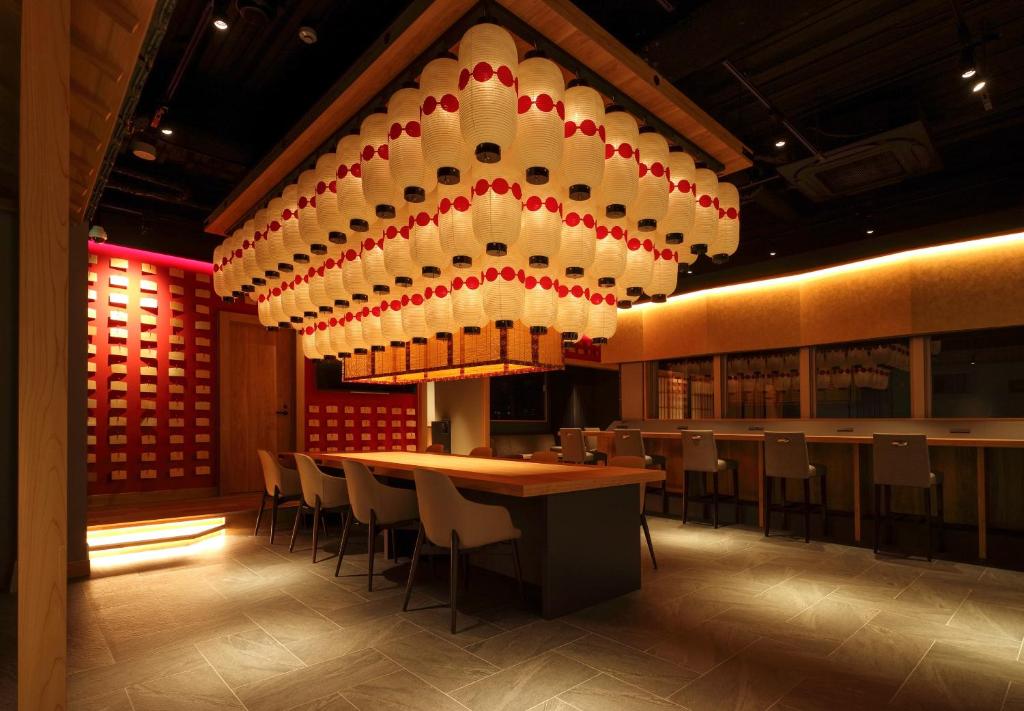 een restaurant met een grote kroonluchter en een tafel en stoelen bij NINJA & GEISHA in Osaka