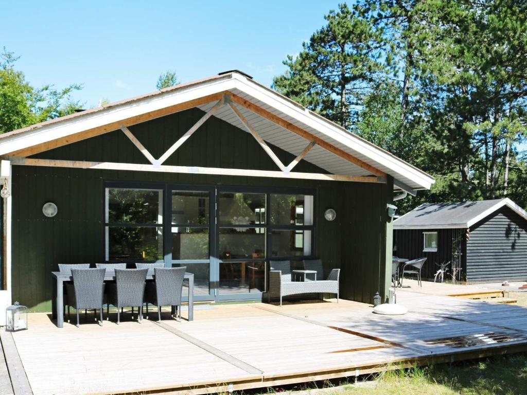 una casa verde con una mesa y sillas en una terraza en Holiday home Hadsund XLVI en Odde