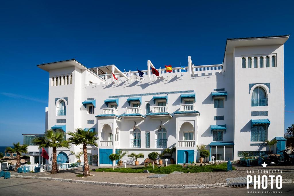 a white building with blue shutters on it at Palais du Calife Riad Spa & Clubbing in Tangier