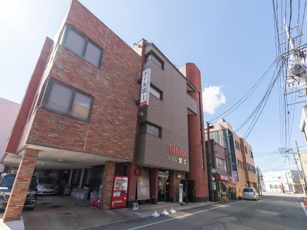 un bâtiment en briques rouges au coin d'une rue dans l'établissement Tabist ホテル富士, à Daisen