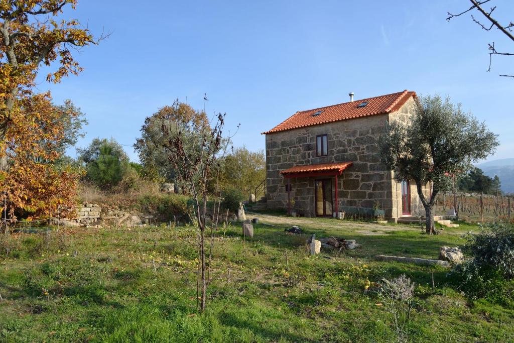 a stone house in a field with some animals in front of it at Retiro da Lameira in Seia