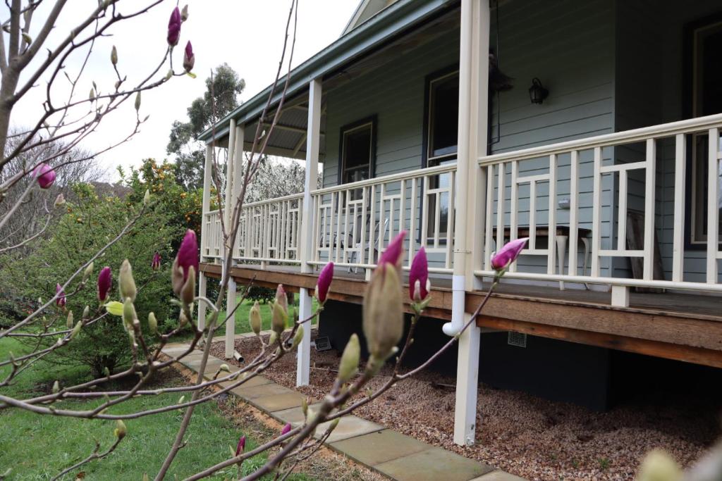 un porche de una casa con flores púrpuras en Lottie’s Bed & Breakfast at Fielderberry Farm, en Cockatoo