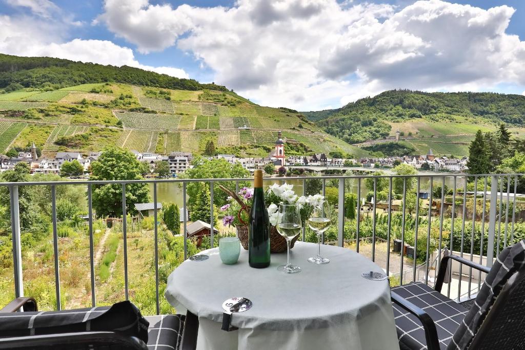 a table with wine glasses on a balcony with mountains at Ferienwohnung Ankerplatz in Zell an der Mosel