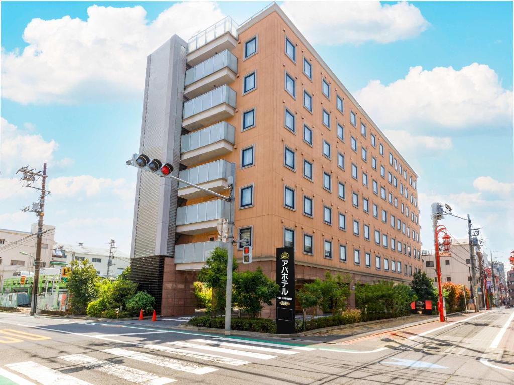 ein hohes Gebäude in einer Stadtstraße mit Ampel in der Unterkunft APA Hotel Haneda Anamori Inari Ekimae in Tokio