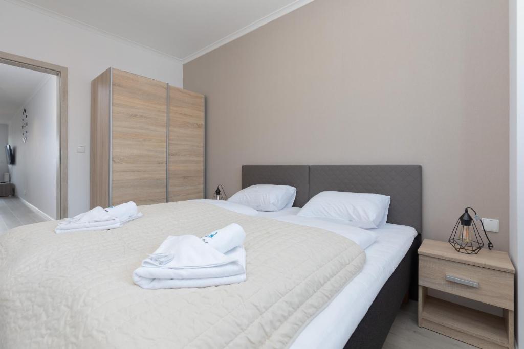een slaapkamer met 2 witte handdoeken op een bed bij Przestronny Apartament z Balkonem - Przy Porcie - Świnoujście by Renters in Świnoujście