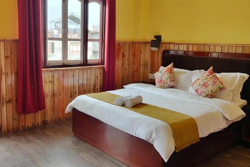 a bedroom with a large bed with red curtains at Pelling Hotel Ladakh House in Pelling