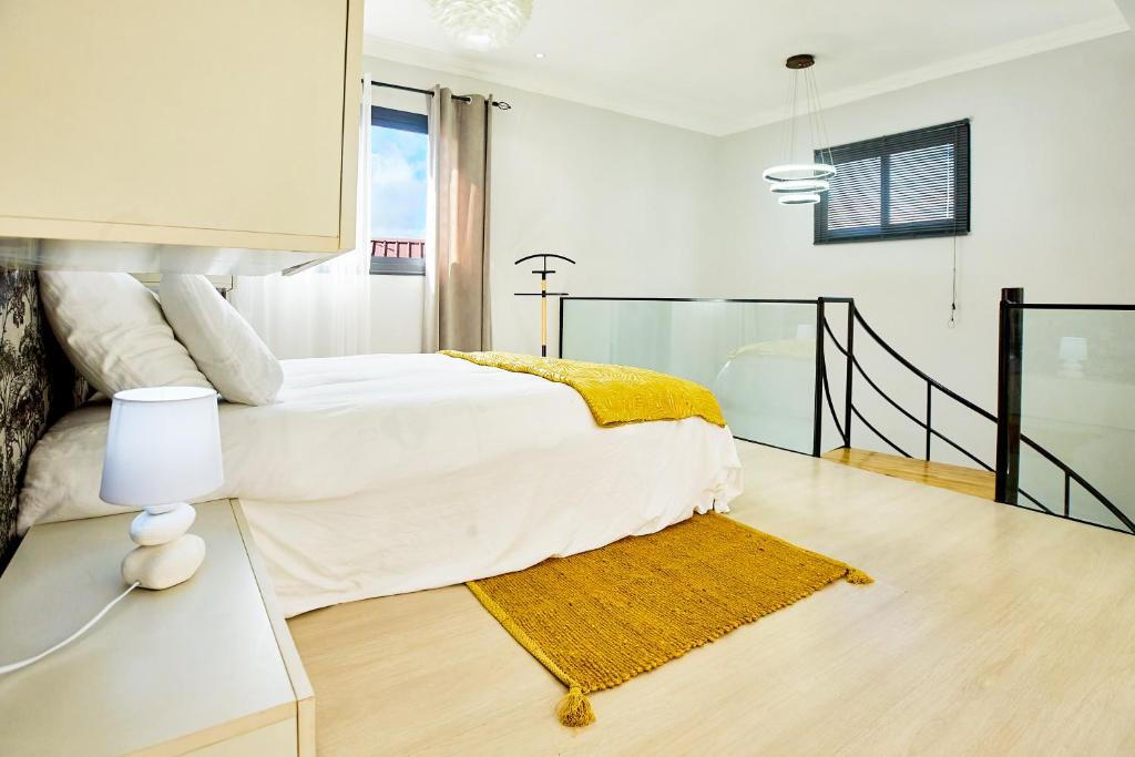 Dormitorio blanco con cama y alfombra amarilla en Tranokely en Antananarivo