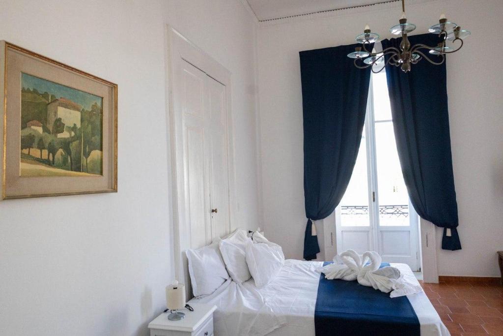 - une chambre avec un lit doté de rideaux bleus et d'une fenêtre dans l'établissement Palazzo Bonaventura 1906, à Ischia