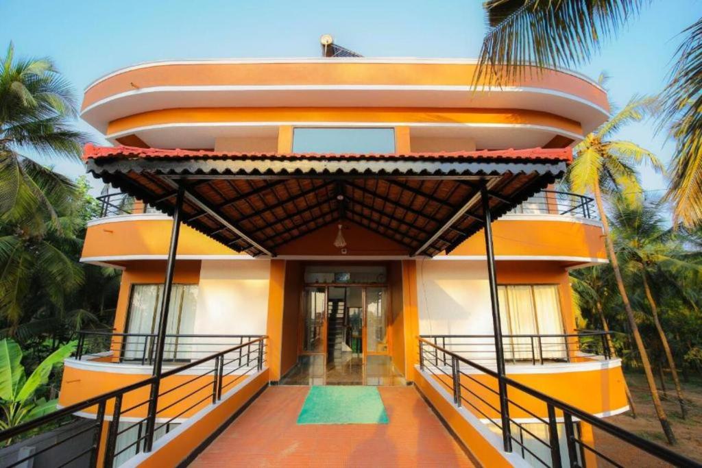 a house with an orange facade and palm trees at SAIKUSHI BEACH RESORT in Kundapur