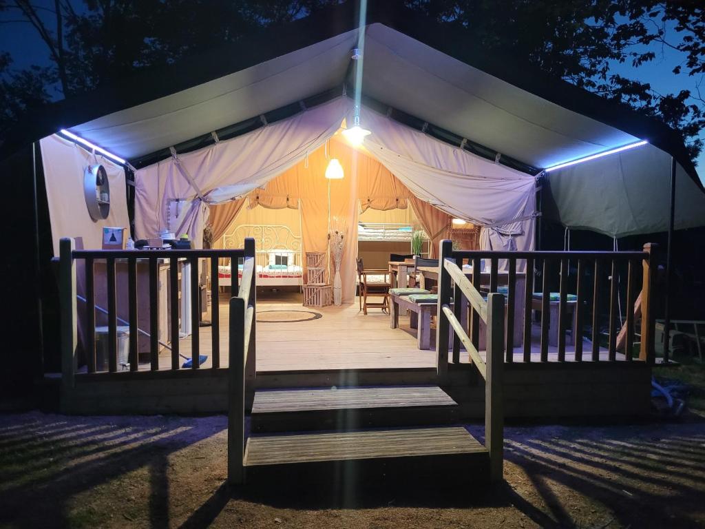 a tent with a wooden porch at night at Tente Lodge Safari in Saint-Martin-des-Besaces