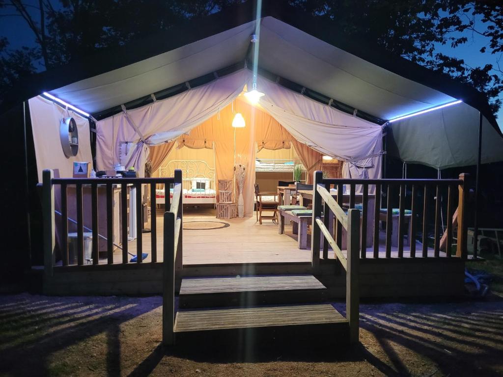 namiot z drewnianą werandą w nocy w obiekcie Tente Lodge Safari w mieście Saint-Martin-des-Besaces