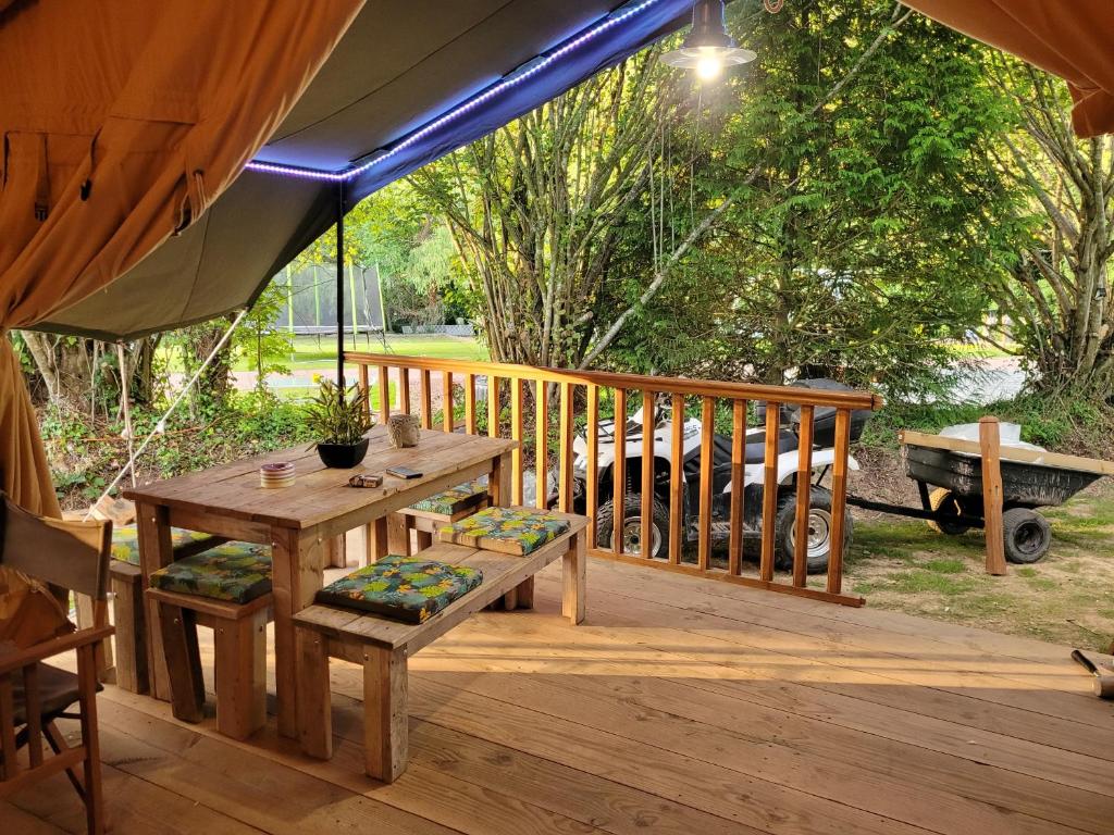 drewniany taras ze stołem piknikowym i namiotem w obiekcie Tente Lodge Safari w mieście Saint-Martin-des-Besaces