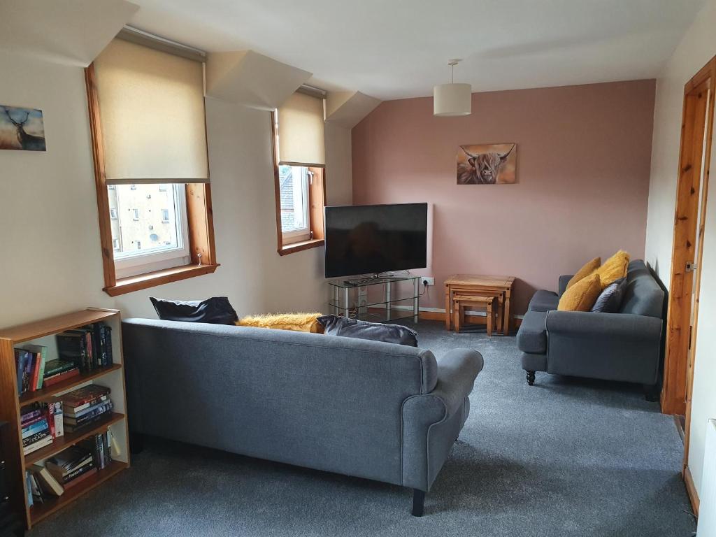 sala de estar con sofá y TV en Nelson Street Apartment en Inverness