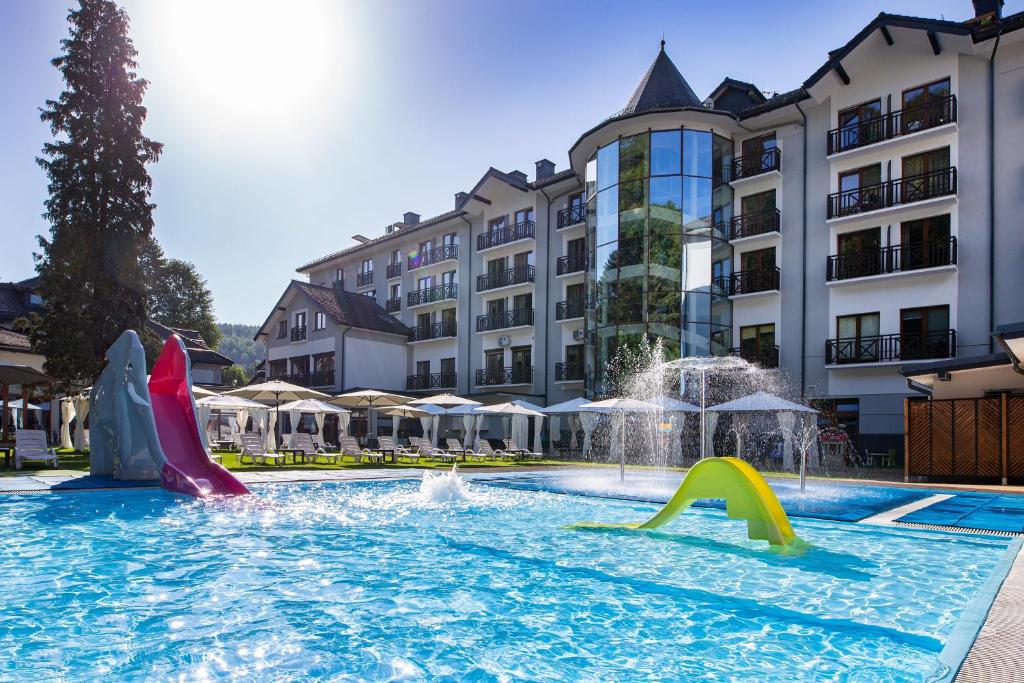 a swimming pool with slides in front of a hotel at Hotel Verde Montana Wellness & Spa in Kudowa-Zdrój