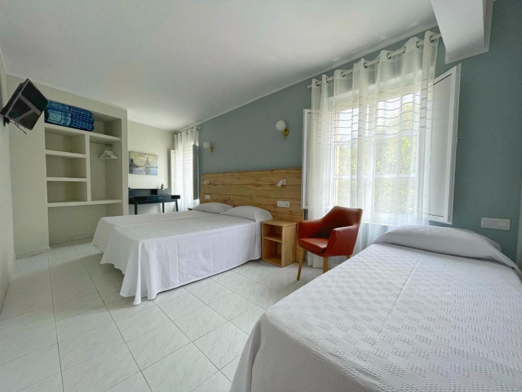 a bedroom with two beds and a chair and a window at Grupo Las Catedrales - Casa Amadora in Barreiros