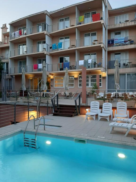 a swimming pool with chairs and a building at Hotel Tamaris in Novi Vinodolski