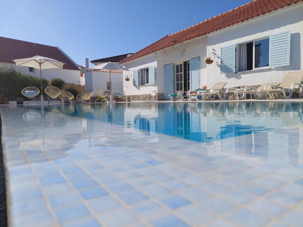 a swimming pool in front of a house at Villa Mariana Piscina Privada in Porto Covo
